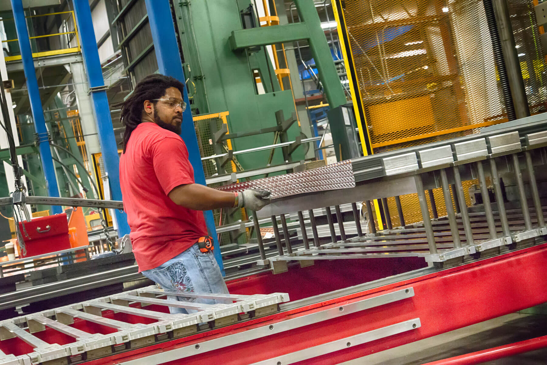 A man wearing safety goggles and gloves works with equipment at AAON company in Longview, Texas